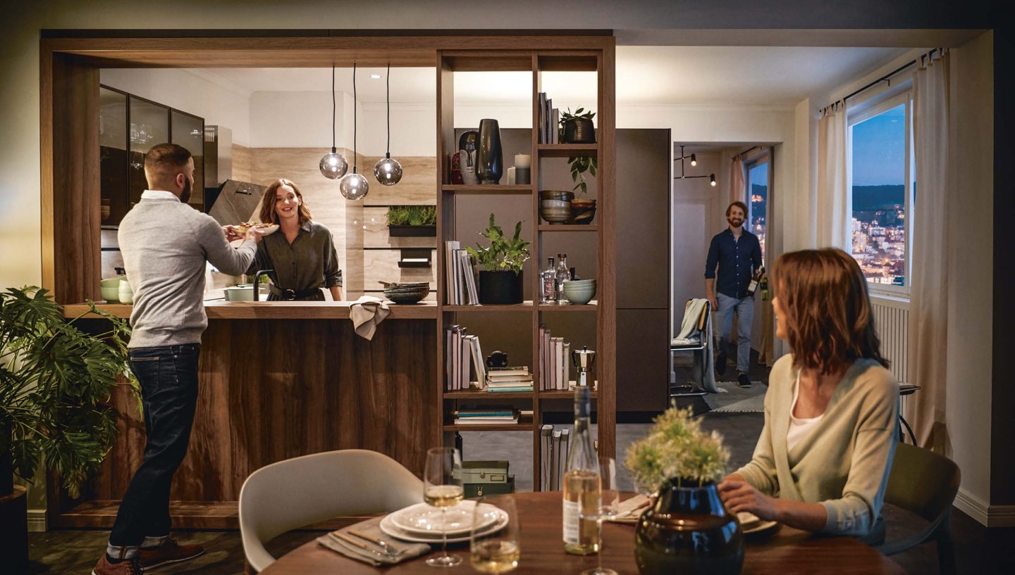 Eine Gruppe kocht gemeinsam on eoner modernen Nussbaumküche un U-Form mit offenem Essbereich.