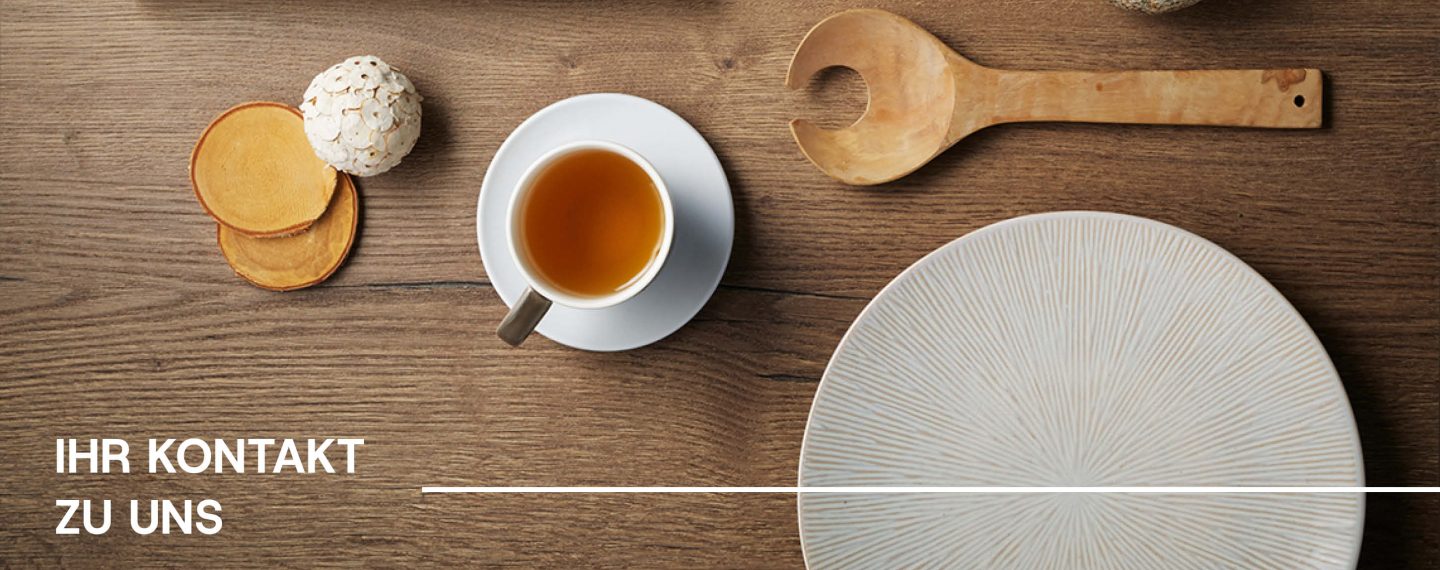 Assortment von Tellern, Tee und Löffeln auf einer Holzplatte. Darauf steht 