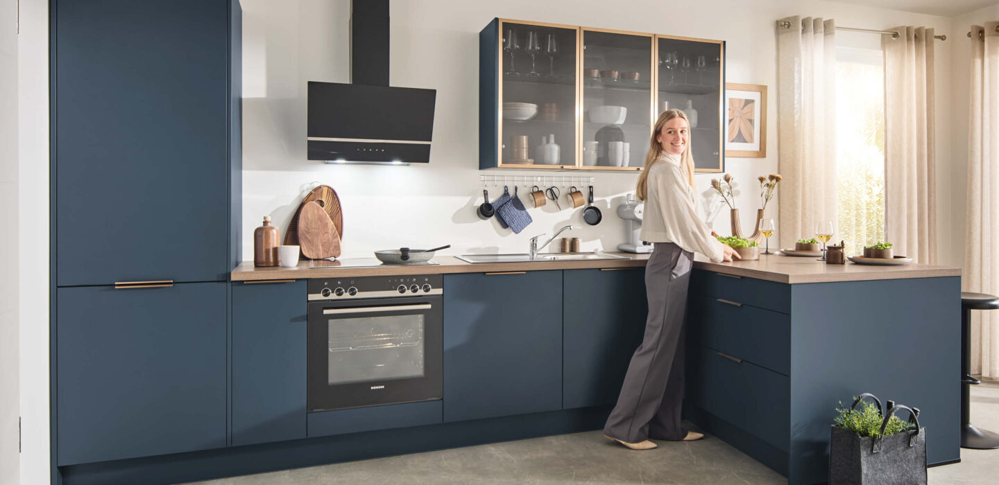 Moderne Küche in elegantem Blau mit Glasoberschränken und Insel – stilvolles Wohnkonzept für zeitgemäße Raumgestaltung.