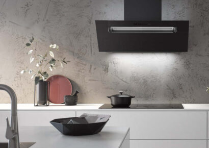 Berbel Dunstabzugshaube in Schwarz mit LED-Beleuchtung über Kochfeld, kombiniert mit moderner Küchenzeile und strukturierter Nischenrückwand