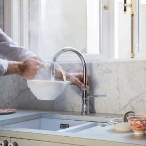 Quooker Kochendwasserhahn in Chrom mit Dampfentwicklung, über Spüle in moderner Küche, ermöglicht sofort heißes Wasser für komfortables Arbeiten