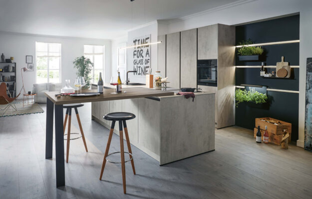 Moderne Schüller Küche mit Kochinsel in Betonoptik, Holztheke, integrierten Geräten und offenem Regal mit Beleuchtung im hellen Wohnraum