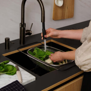 Quooker Flex Armatur in Gunmetal mit ausziehbarem Schlauch, über schwarzer Spüle in moderner Küche, ideal zum Abspülen von Gemüse und flexiblem Arbeiten