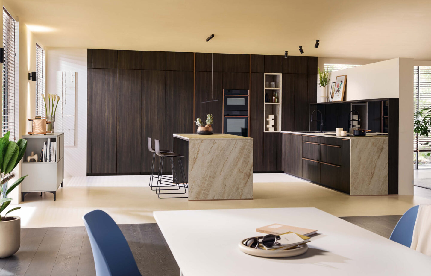 Moderne Schüller Küche mit Kochinsel aus Naturstein und dunklen Holzfronten im Küchenstudio Helmke