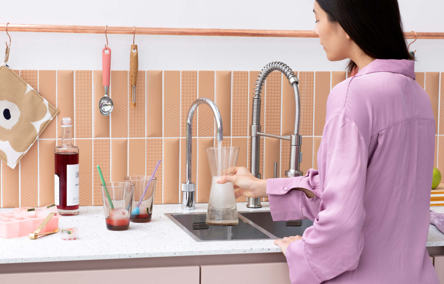 Person füllt Karaffe mit Wasser aus moderner Quooker Armatur in stilvoller Küche