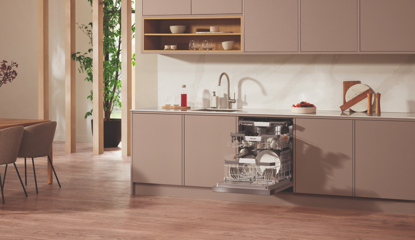 Geöffneter Miele-Einbaugeschirrspüler mit beladenen Geschirrkörben in einer modernen Küche.